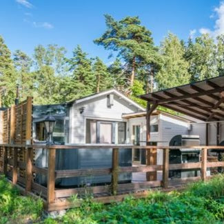 Modern cabin with wooden deck and outdoor sauna in a forest setting